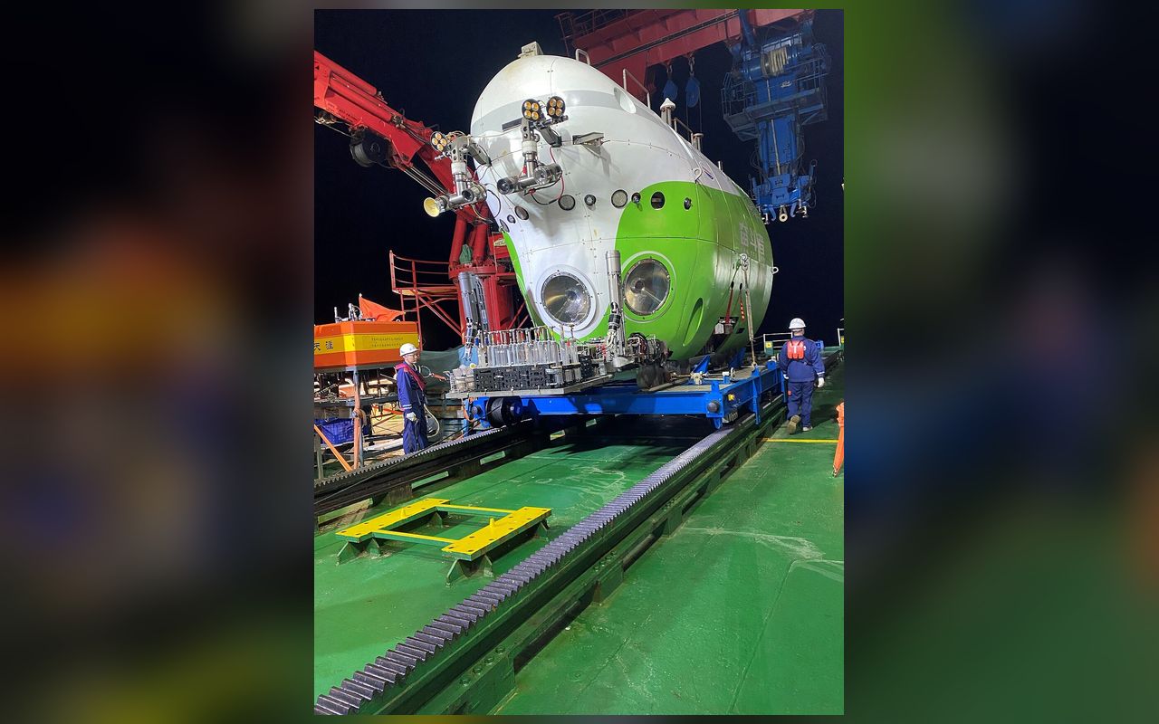 夜间停靠在母船甲板上的白绿相间的“奋斗者”号潜水器